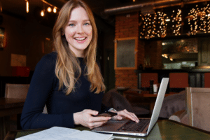 jeune femme souriante devant son ordinateur portable qui travaille