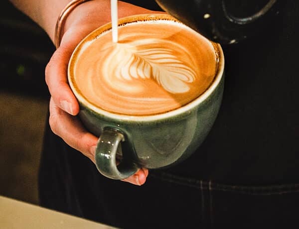 Une personne préparant une tasse de café latte